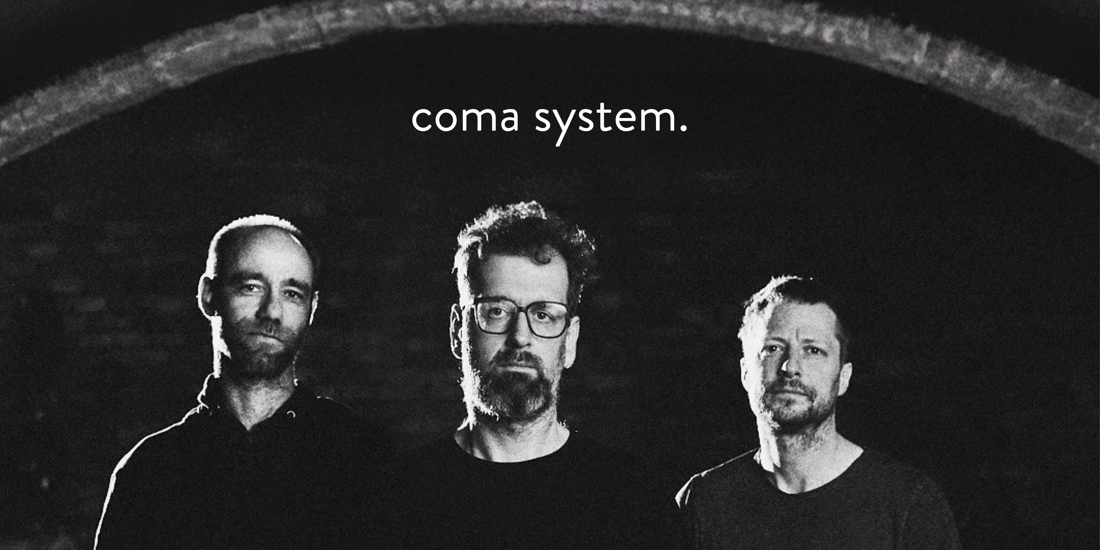 Die Band "Coma System". Drei Personen stehen unter einem Gewölbebogen, blicken in die Kamera. Oben in der Mitte das Logo der Band.