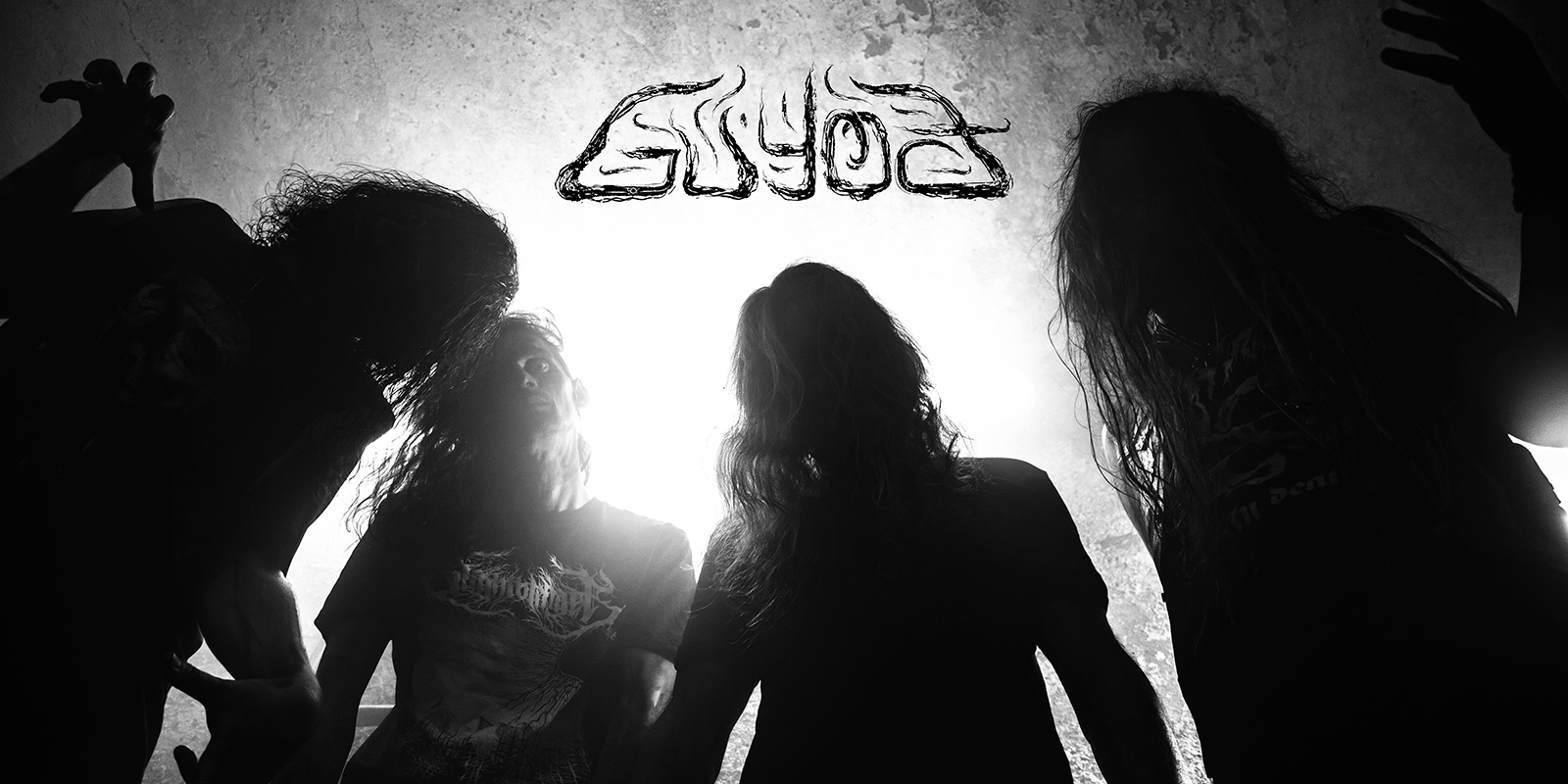 Die Band "Guyođ". Vier Personen, von unten fotografiert, von hinten beleuchtet. Oben in der Mitte das Logo der Band.