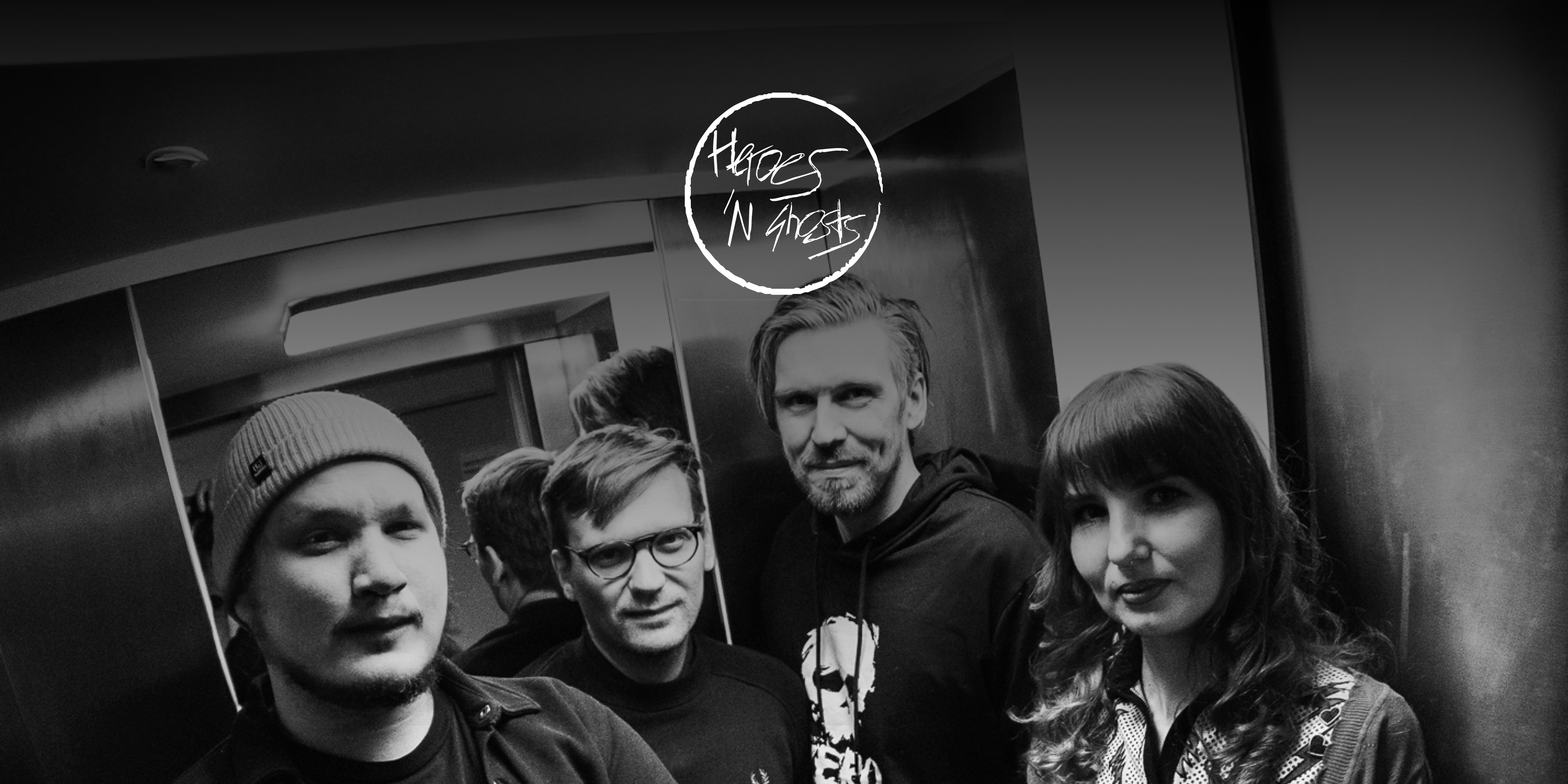 Die Band "Heroes 'n Ghosts". Vier Personen in einem Fahrstuhl blicken in die Kamera. Oben in der Mitte das Logo der Band.
