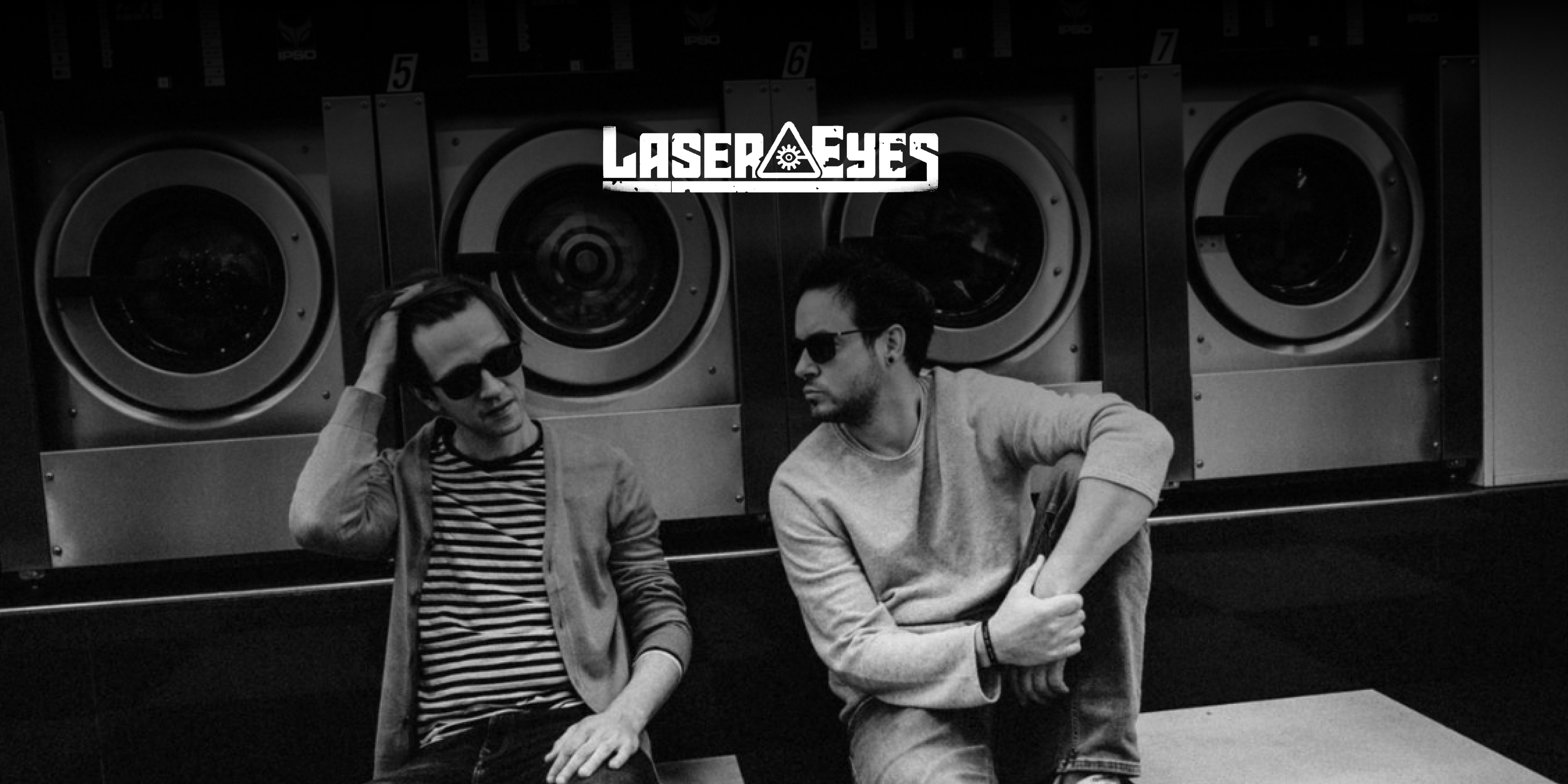 Die Band "Laser Eyes". Zwei Personen sitzen in einem Waschsalon auf dem Boden.