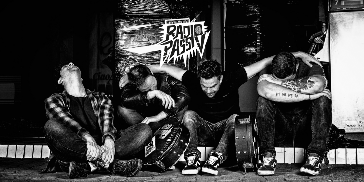 Die Band "Radio Passiv". Vier Männer sitzen auf dem Boden.